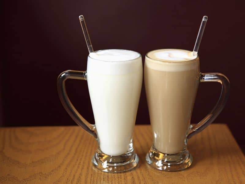 A glass of frothy milk and a skinny latte