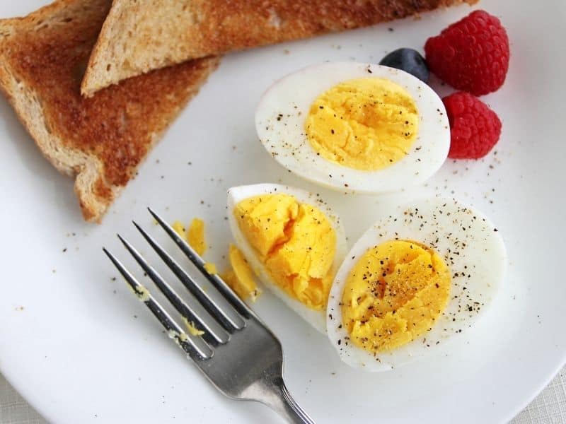 Breakfast plate with toast, raspberries, and a hard boiled egg